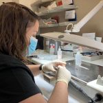 Prothésiste dentaire fabriquant une couronne en zircone dans un laboratoire de prothèses dentaires équipé de technologies numériques.