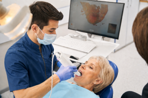 Dentiste utilisant un scanner intra-oral pour réaliser une empreinte numérique chez une patiente senior dans une clinique dentaire moderne.