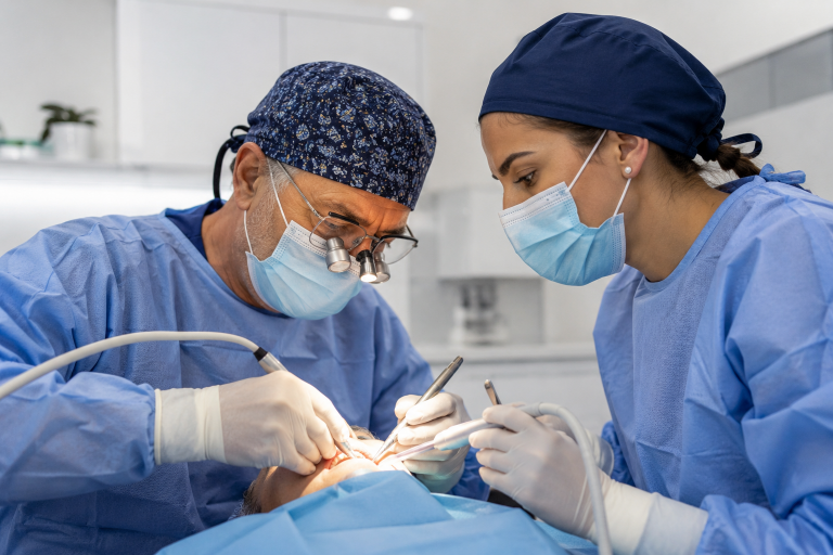 Deux chirurgiens-dentistes portugais réalisent une intervention implantaire dans un cabinet moderne.